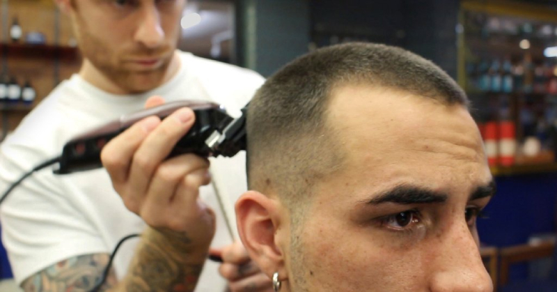 The barber is giving a buzz cut to the man after FUE hair transplant