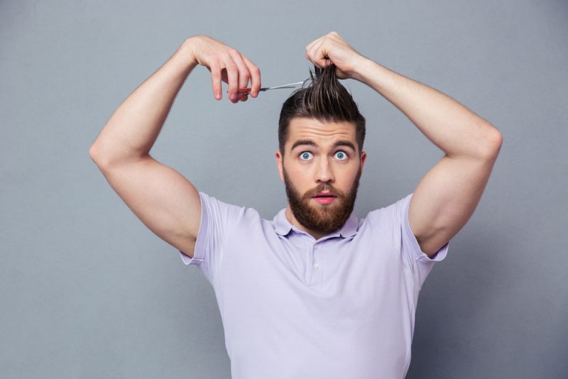 Blue eyed man cutting his own hair