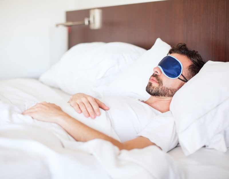 Man Sleeping in a Hotel Room With a Sleep Mask
