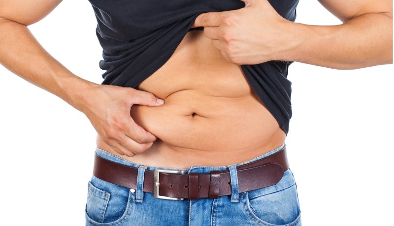 Fotografía de un hombre que se levanta la camiseta y se agarra la grasa del abdomen