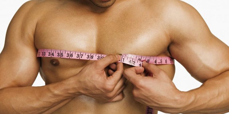 Foto de un hombre con plano cercano de torso bronceado medido con cinta de medir